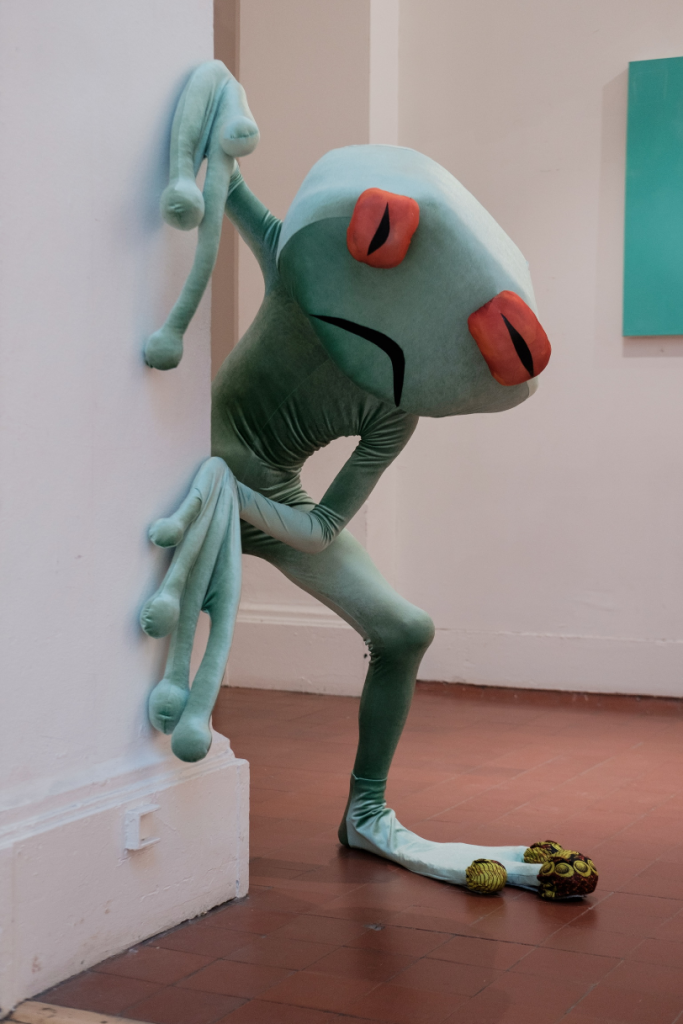frog costume peering around a wall